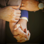 person in blue long sleeve shirt holding babys hand